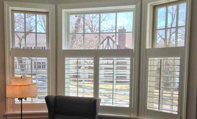 Bottom half white shutters in family room bay window.